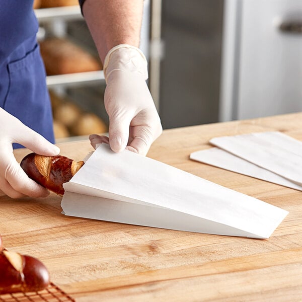 A person putting a piece of bread in a Bagcraft Dubl Wax bread bag.