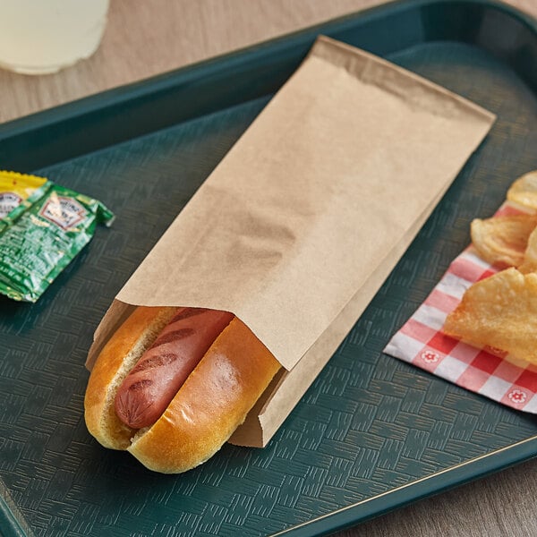 A Bagcraft EcoCraft paper bag with a hot dog inside on a tray.