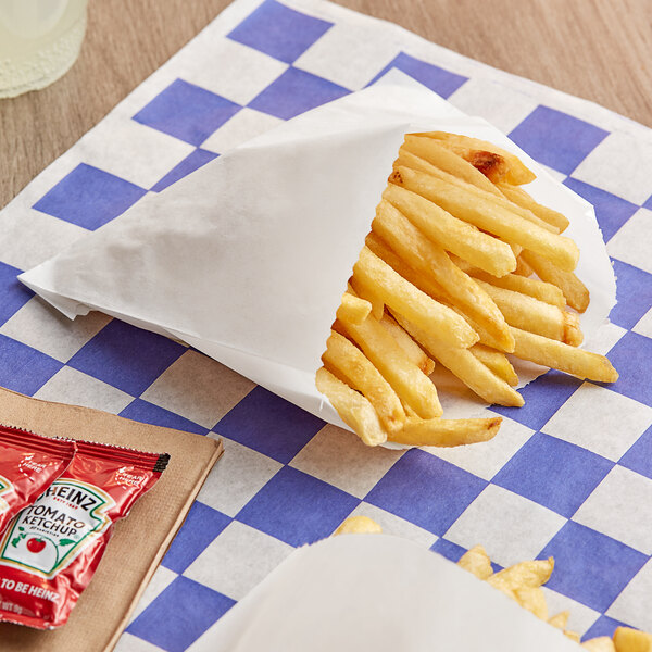 French fries in a Bagcraft white paper wrapper on a checkered table with ketchup.