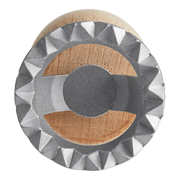 A close up of a metal and wooden Imperia Circle Ravioli Cutter Stamp.