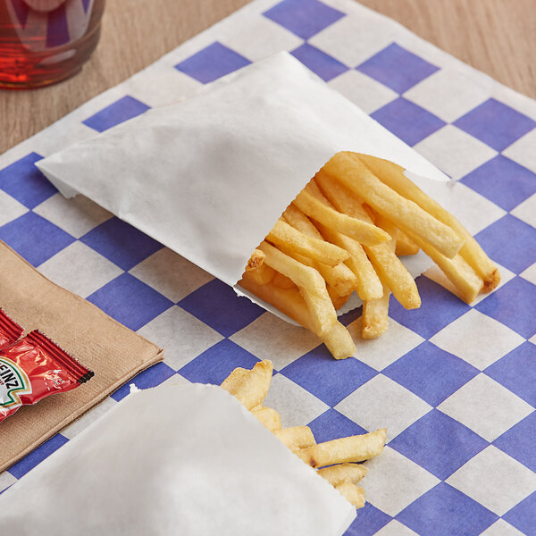 A pile of french fries in a white Bagcraft paper bag.