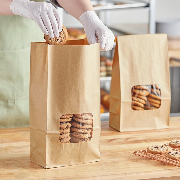 A person wearing gloves putting a cookie in a Bagcraft natural tortilla chip bag.