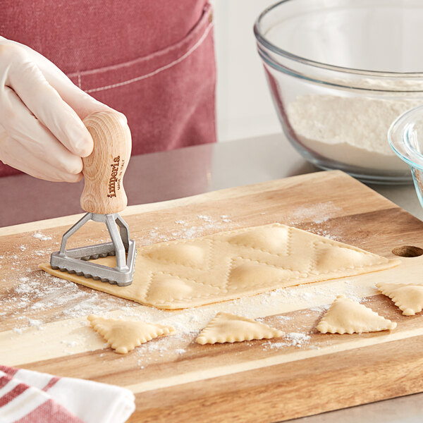 A person using a dough cutter to make ravioli.