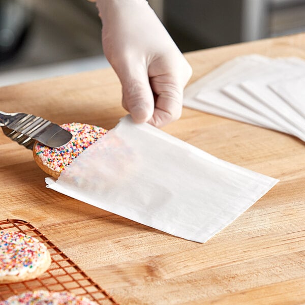 A person using a metal object to cut a cookie on a counter in a bakery display.