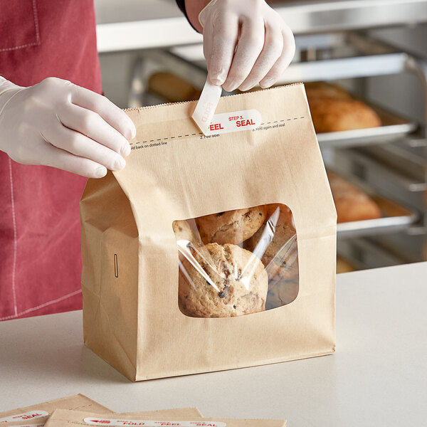 A person in a white apron putting a bag of cookies in a Bagcraft natural bakery bag with a Tac Seal.