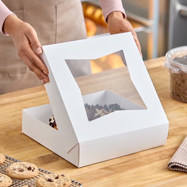 A woman holding a Baker's Lane pie box with a clear window.
