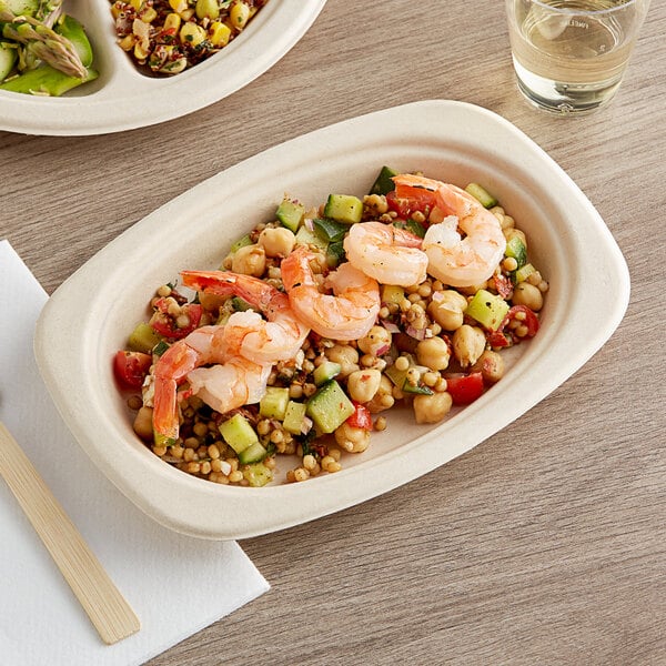 A World Centric compostable oval fiber plate with food on a table.