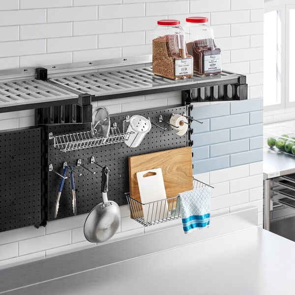 A black Cambro Camshelving task station with a container and utensils on the shelf.