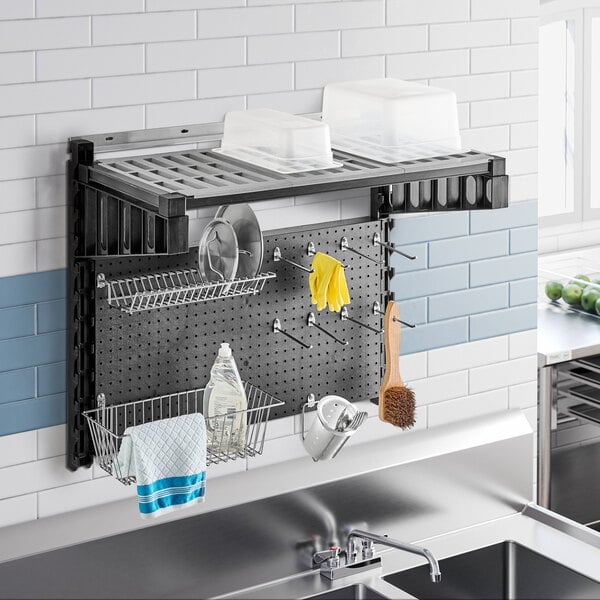 A black metal Cambro Camshelving® sink station above a kitchen sink with dishes and other items on it.