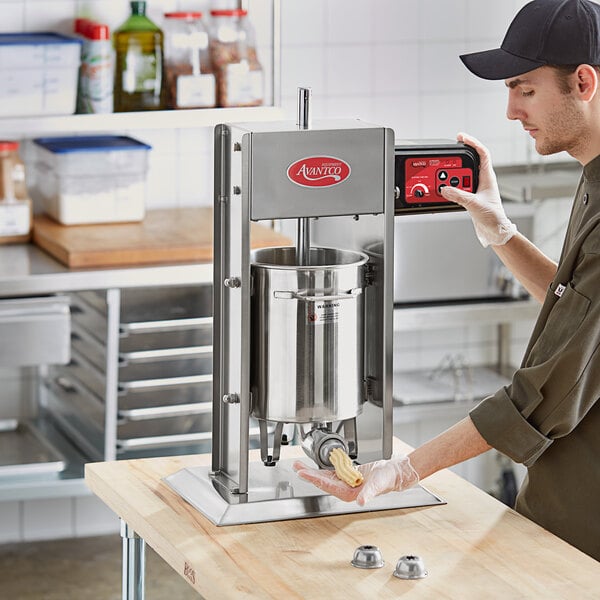 A man using an Avantco stainless steel churro stuffer on a counter in a professional kitchen.