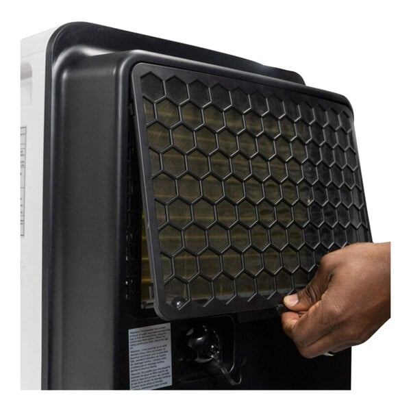 A person holding a black filter over a white Danby dehumidifier.