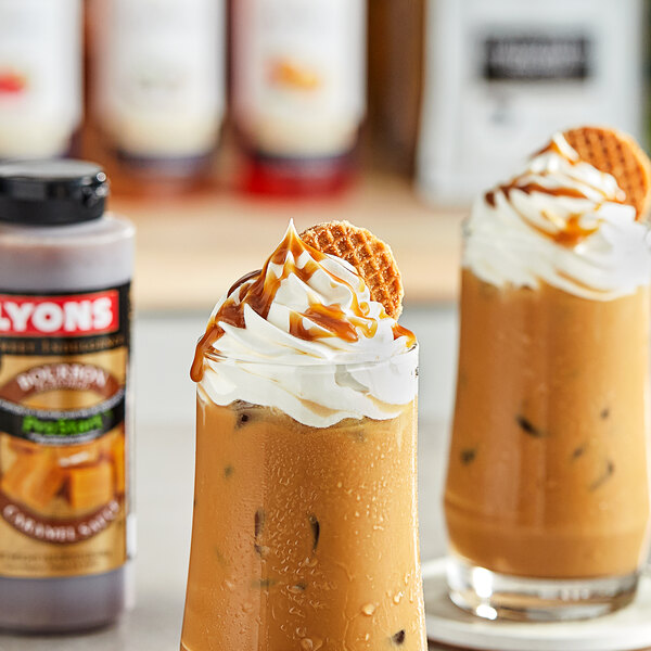 A glass of iced coffee with whipped cream and Lyons Sweet Indulgence Bourbon Caramel Flavoring Sauce on a table.