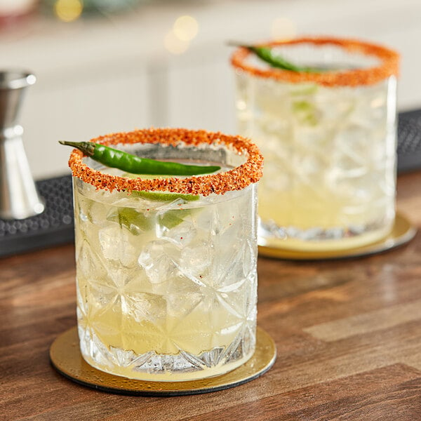 Two glasses of Maui by Lyons Margarita Smoothie with chili pepper rims on a wooden bar.