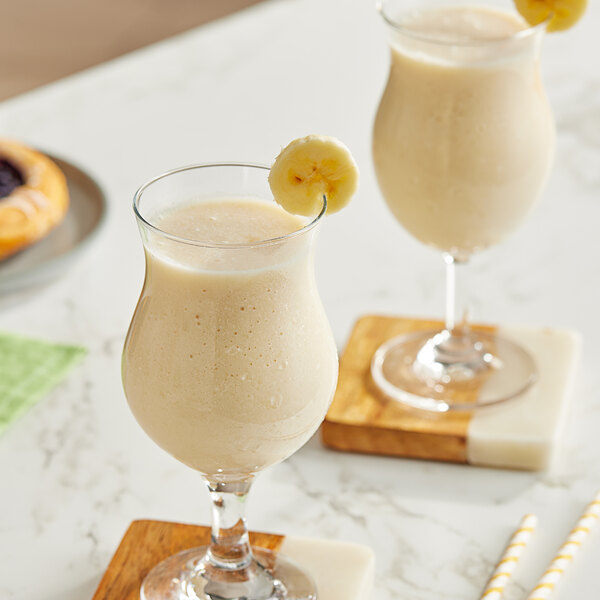 Two glasses of Maui by Lyons banana smoothie with banana slices on top.