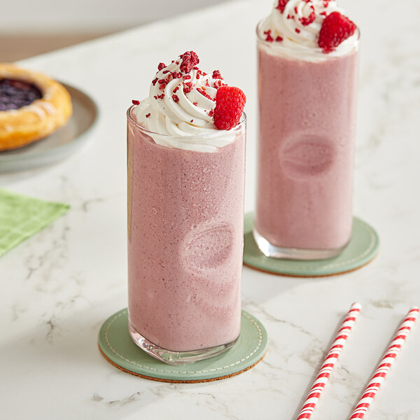 Two glasses of Maui by Lyons Raspberry Smoothies with straws on a table.