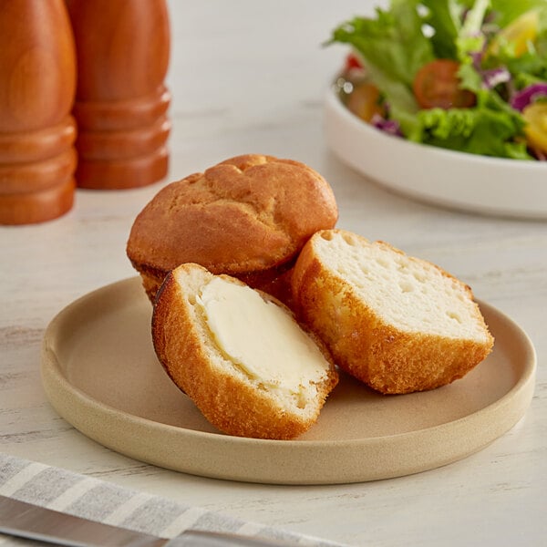 A plate with two Katz Gluten-Free Dinner Rolls on it with a bowl of salad