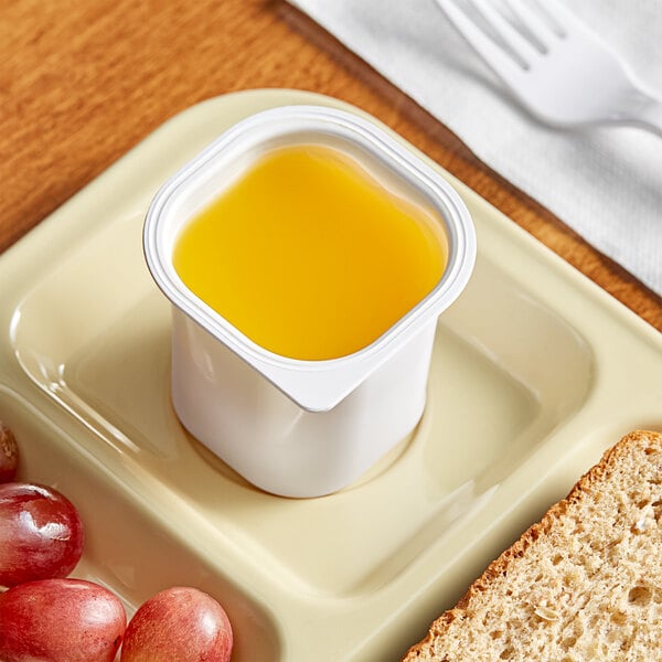 A plate with a cup of Ocean Spray orange juice and grapes.