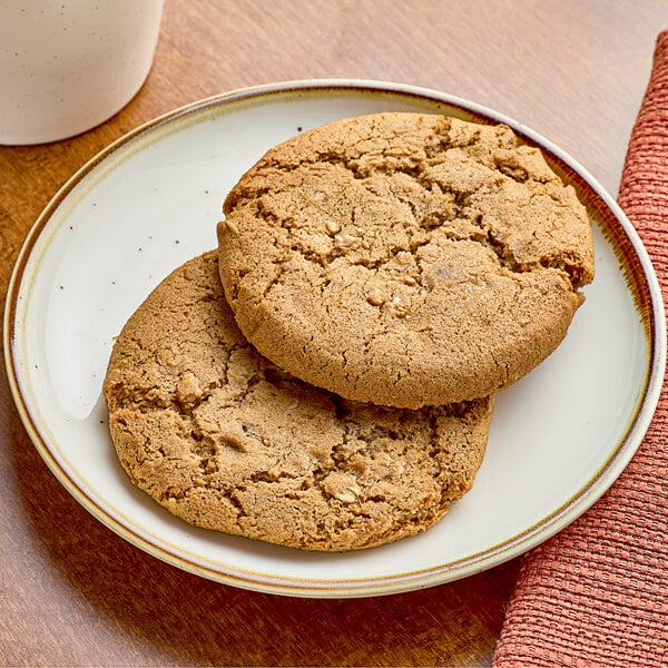 A white plate with two Red Plate Foods Individually Wrapped Vegan Oatmeal Raisin Cookies on it.