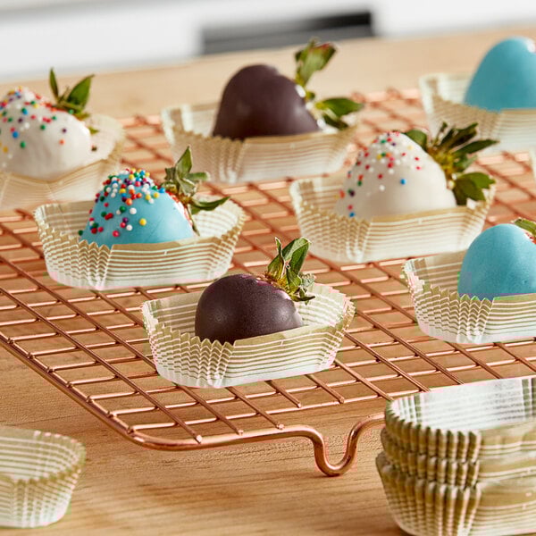 A chocolate covered strawberry in a gold oval cupcake wrapper.