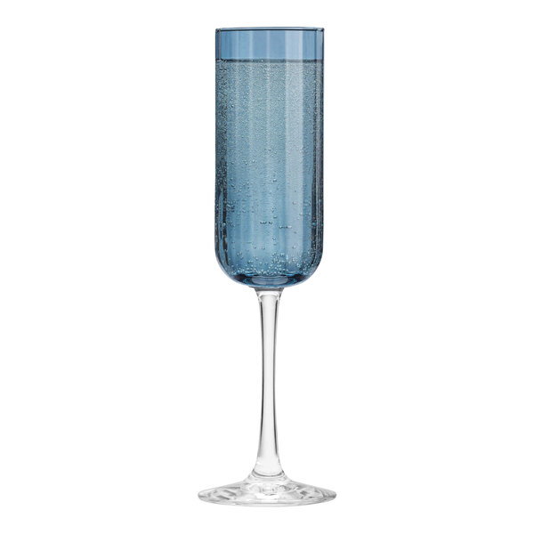 A Libbey blue flute glass with a small amount of blue liquid in it.