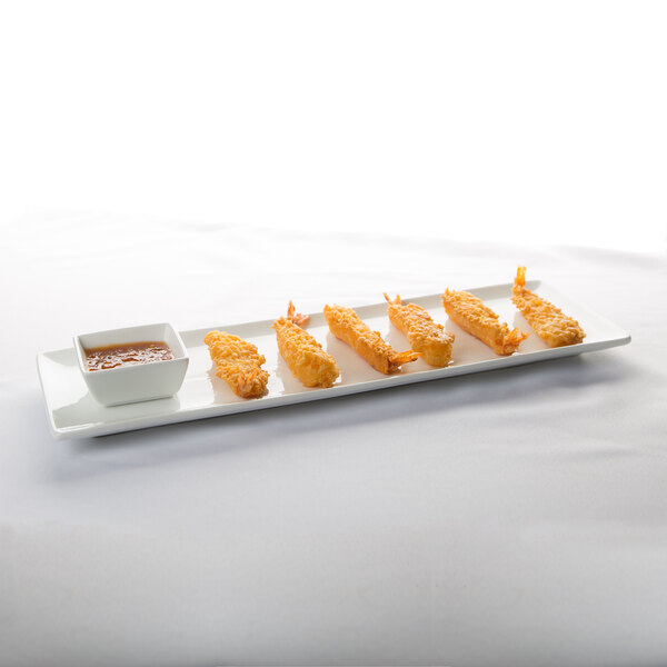 A long, rectangular white porcelain tray with a coupe edge, shown holding fried shrimp and a small square dish of dipping sauce.