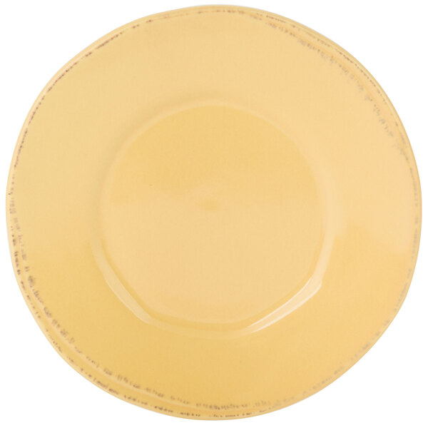 A close-up of a Libbey Farmhouse butter yellow plate with a wide rim and black specks.