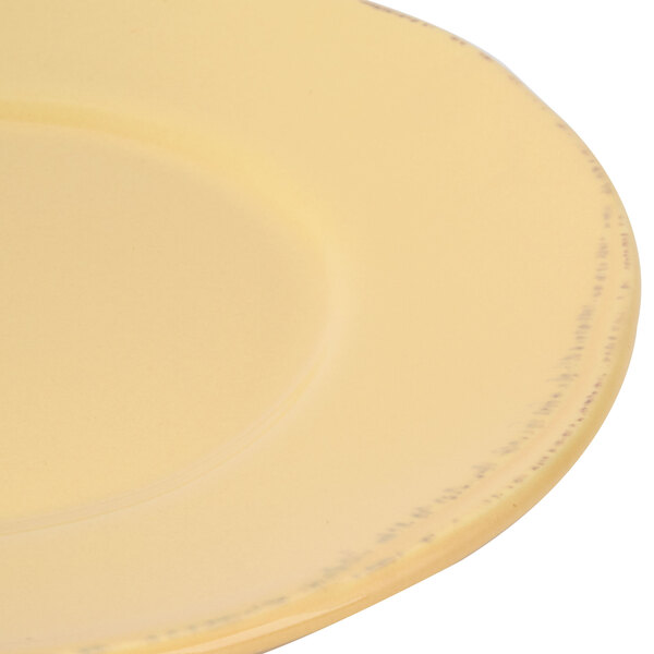 A close-up of a Libbey Farmhouse butter yellow porcelain plate with a wide rim.