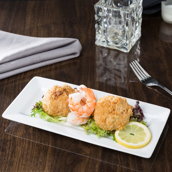 A Libbey rectangular white porcelain plate with shrimp and lemon slices on it.