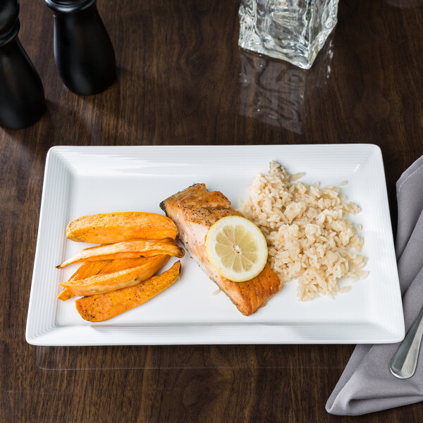 A rectangular white porcelain plate with a wide rim, holding a serving of salmon with a lemon slice, sweet potato wedges, and rice.