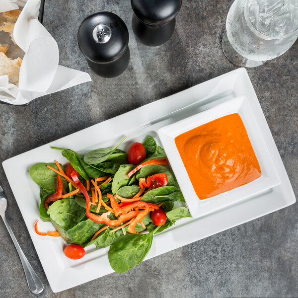 A rectangular white porcelain tray featuring a fresh salad and a bowl of soup.