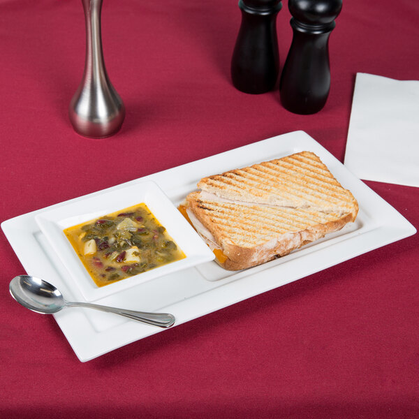 A white porcelain tray with a grilled sandwich and a bowl of soup.