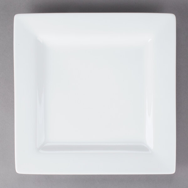 A Libbey Ultra Bright White square porcelain plate with a wide rim on a gray surface.