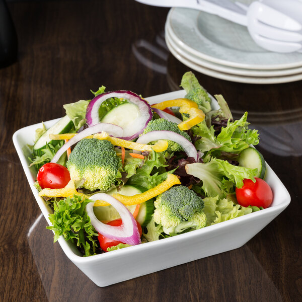 A bowl of vegetable salad on a table with a Libbey Ultra Bright White Square Porcelain Bowl.