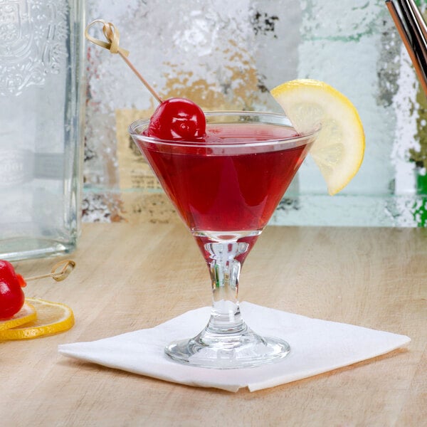 A Libbey Embassy mini martini glass with a red cocktail in it and a lemon wedge.