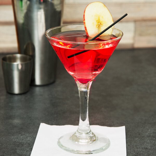 A Libbey martini glass filled with a red cocktail and a slice of apple on the rim.