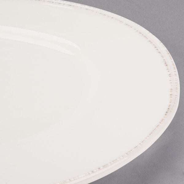 A close up of a Libbey Farmhouse round cream porcelain plate with a wide white rim.