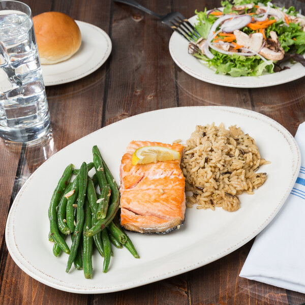 A Libbey oval porcelain platter with salmon, rice, and green beans on a table.