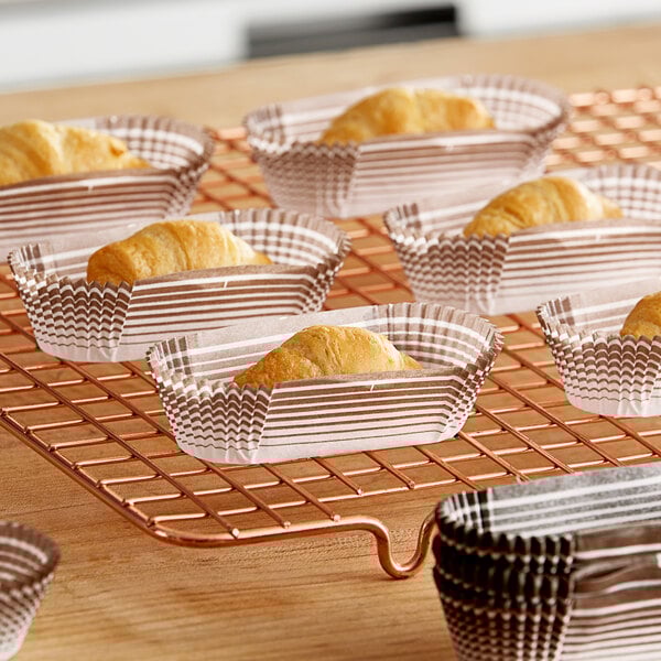 A tray of Novacart brown oval baking cups filled with pastries on a cooling rack.
