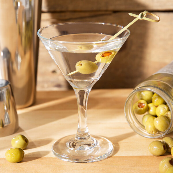A Libbey Embassy martini glass with a martini and olives on a table.