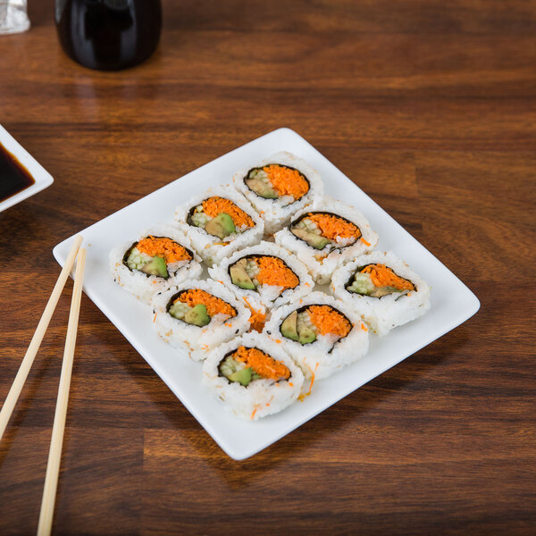 A Libbey Ultra Bright White Coupe Square Porcelain plate with a sushi roll on it.