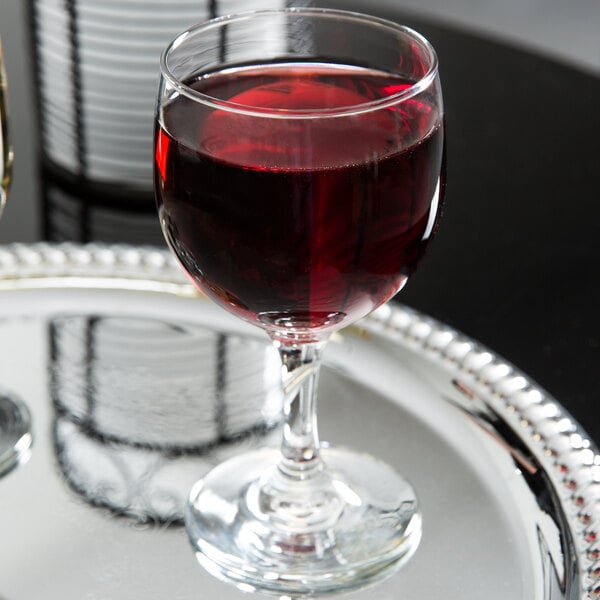 A Libbey Embassy red wine glass of red wine on a silver tray.