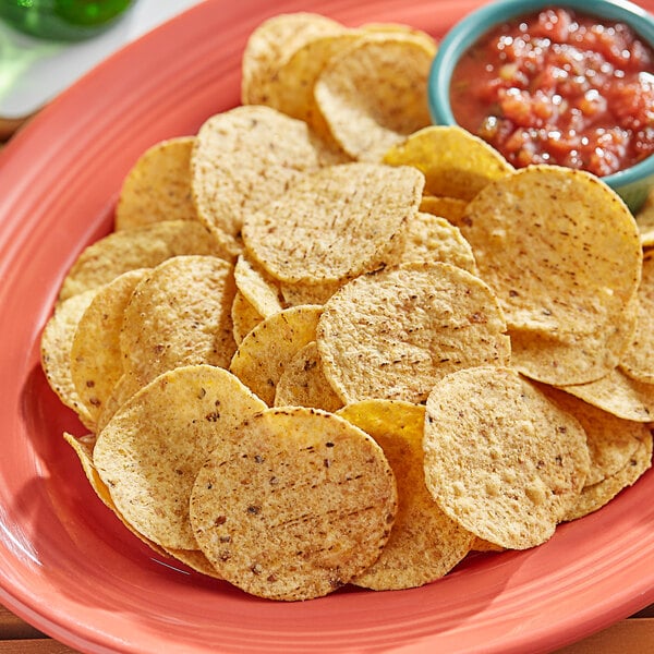 A plate of Clown Whole Grain round tortilla chips with a bowl of salsa.