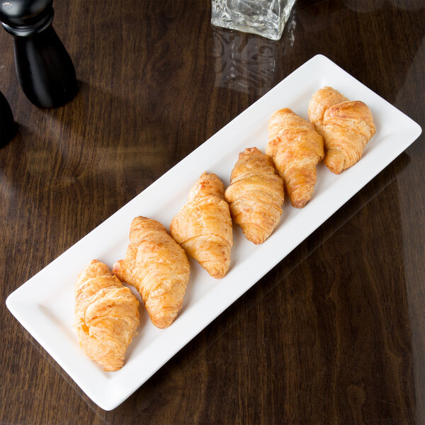A Libbey Ultra Bright White rectangular porcelain plate with croissants on it.