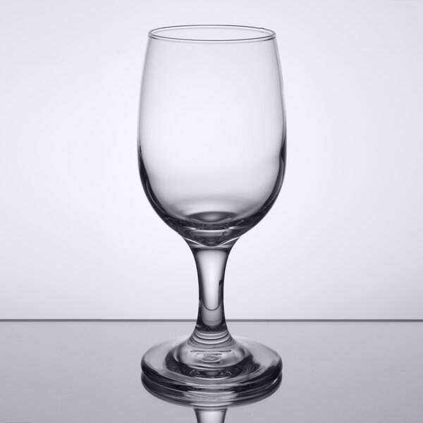 A Libbey white wine glass on a reflective surface.