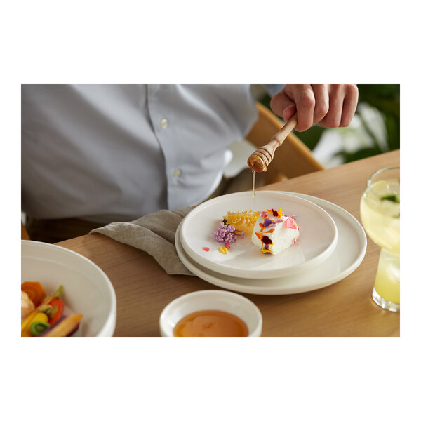 A person eating a piece of cake on a white Libbey Ares plate.