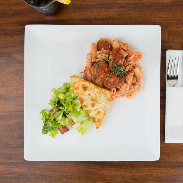 A Libbey Ultra Bright White Coupe Square Porcelain Plate with pasta, meat, and vegetables on a table.