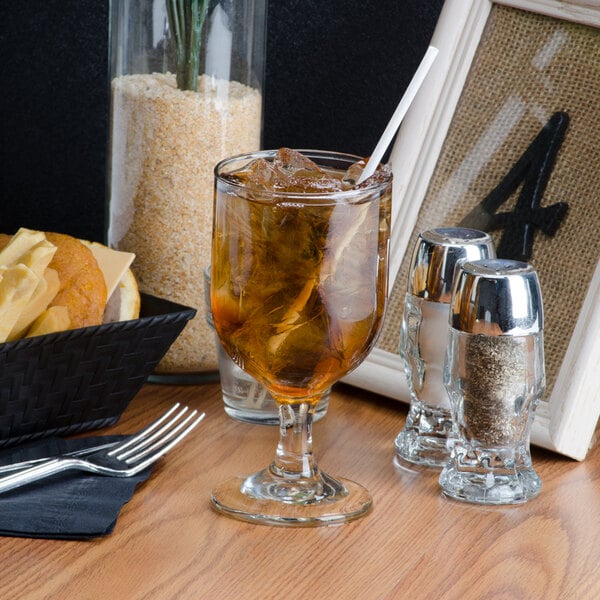 A Libbey goblet filled with brown liquid on a table.