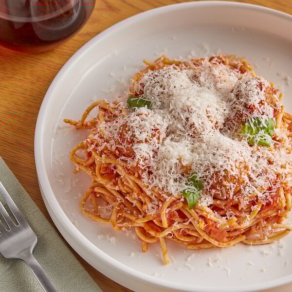 A plate of spaghetti with cheese and meatballs on top.