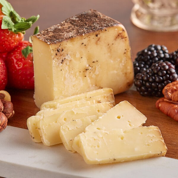 A table with a cheese and fruit board including a wedge of Sartori Espresso BellaVitano cheese.