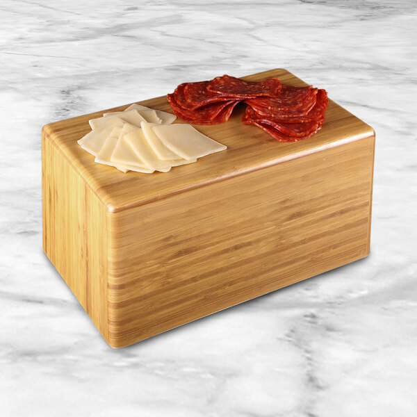 A rectangular faux bamboo display riser with slices of meat and cheese on it.